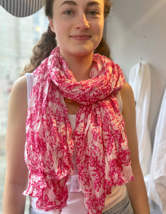 Woman wearing a pink and white patterned scarf in an indoor setting