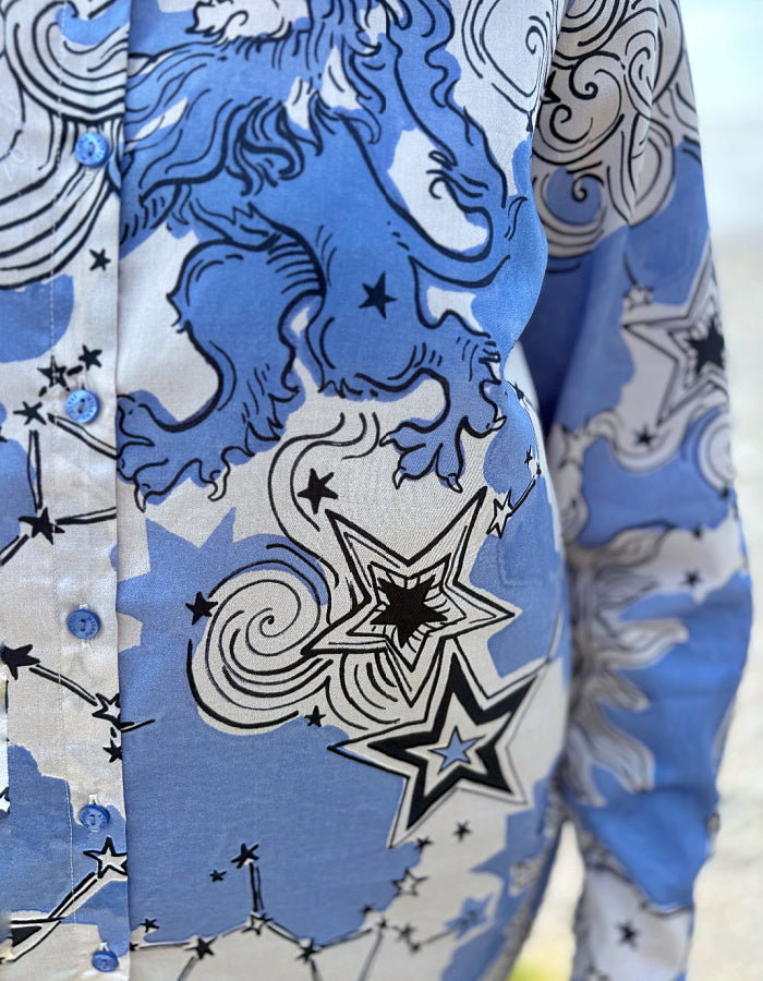 Close-up of a shirt with blue and white pattern featuring stars and celestial designs.