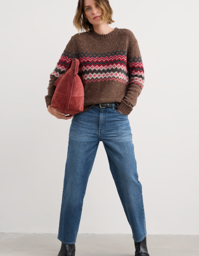 Person wearing brown and pink a fair isle patterned sweater with a neutral background