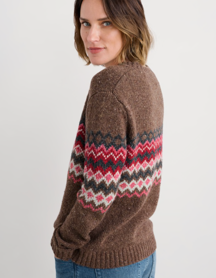 Person wearing brown and pink a fair isle patterned sweater with a neutral background
