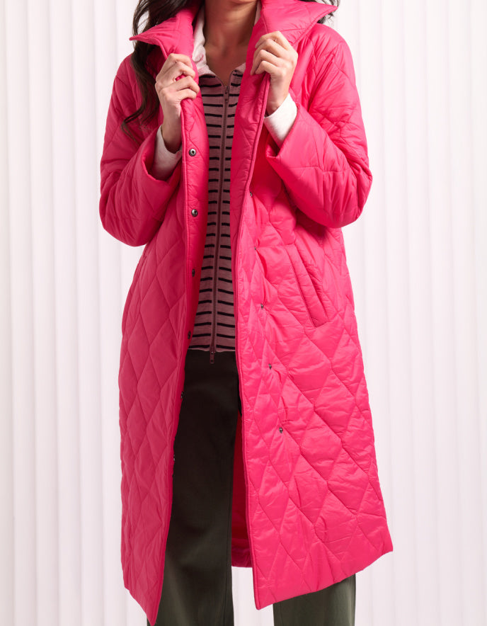 Woman wearing a bright pink midi length puffer coat against a white background
