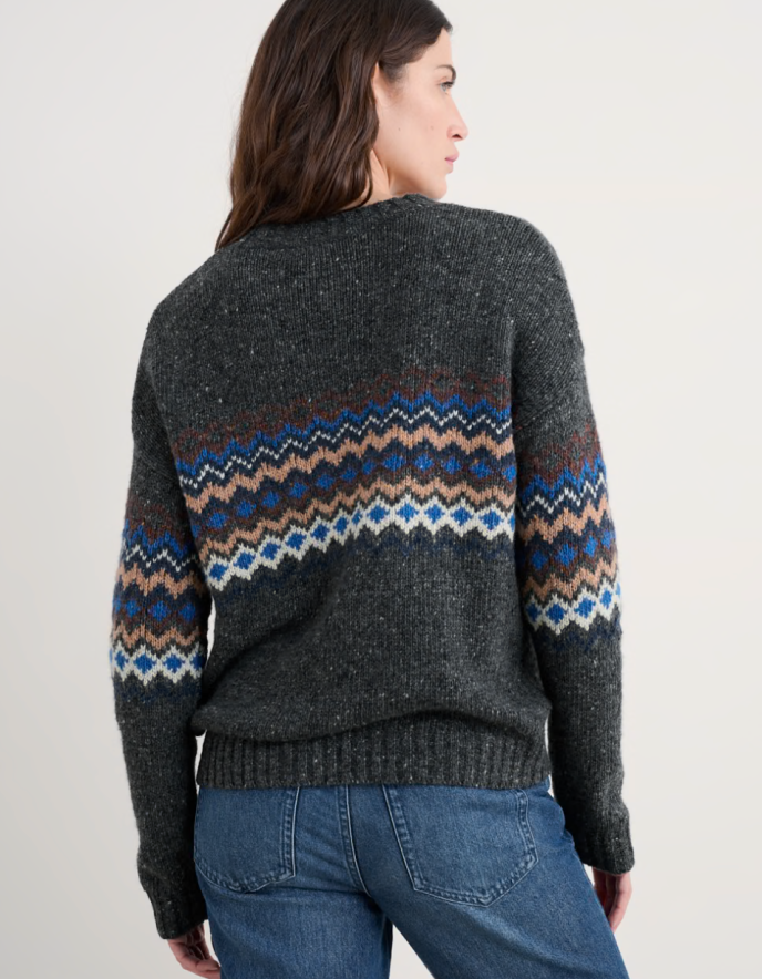 Woman wearing a dark grey tweed sweater with fair isle patterned against a white background