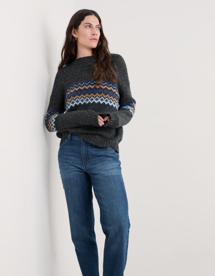 Woman wearing a dark grey tweed sweater with fair isle patterned against a white background