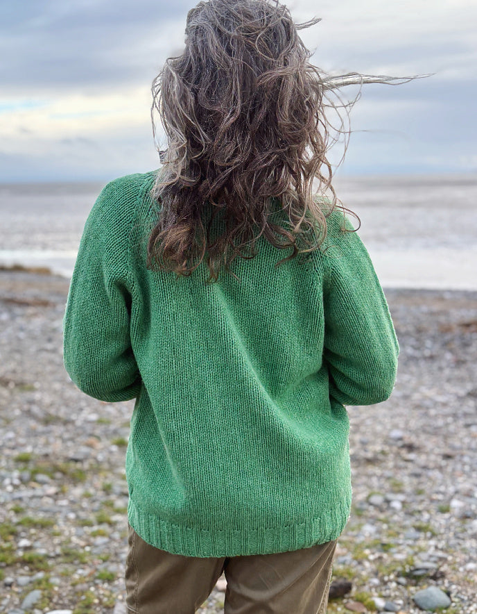 woman wearing green v neck wool cardigan on a beach
