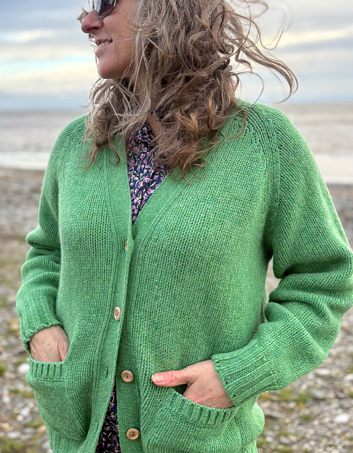 woman wearing green v neck wool cardigan on a beach