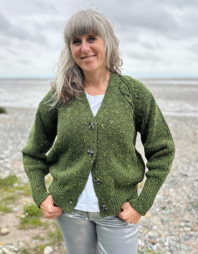 Person wearing a donegal tweed green knitted cardigan in a natural setting