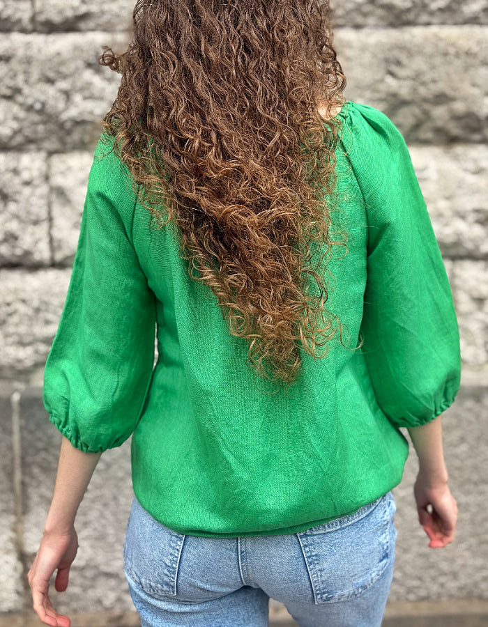 green linen top with elasticated scoop neckline that can be worn off shoulder and adjustable was it. with 3/4 length sleeves