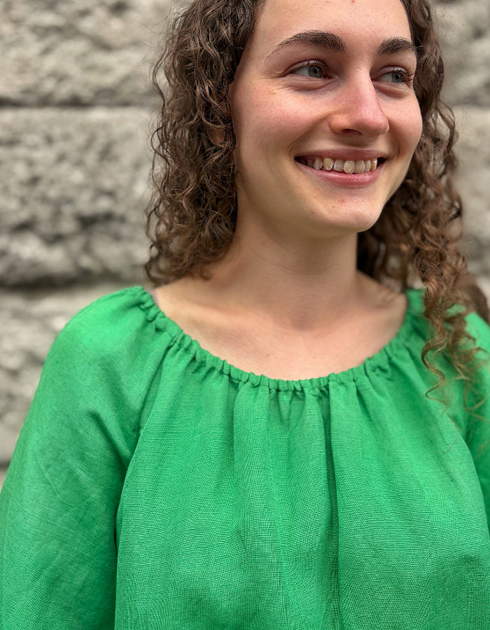 green linen top with elasticated scoop neckline that can be worn off shoulder and adjustable was it. with 3/4 length sleeves