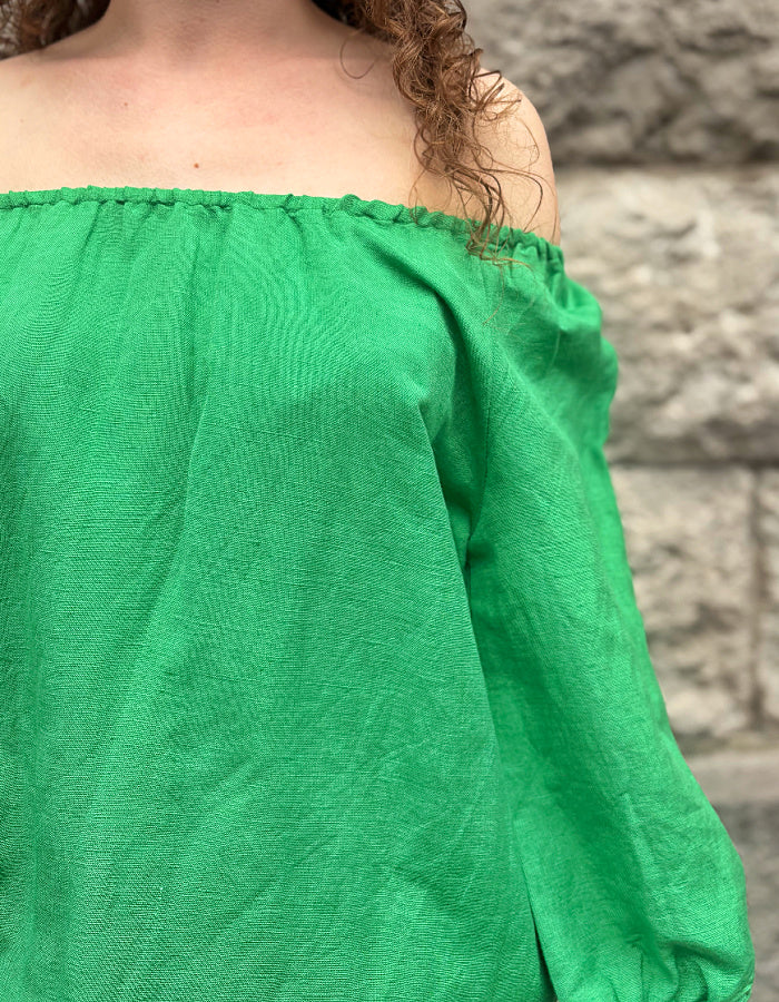 green linen top with elasticated scoop neckline that can be worn off shoulder and adjustable was it. with 3/4 length sleeves