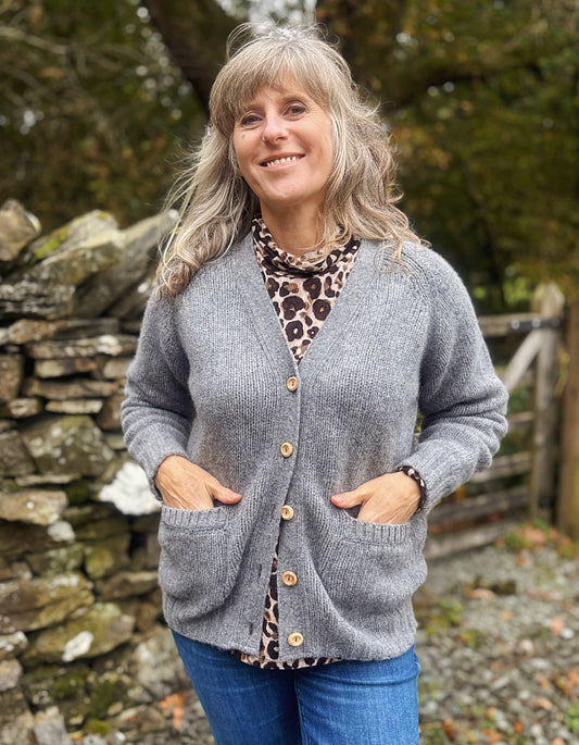 Woman wearing a gray cardigan with a leopard print shirt in a natural setting.