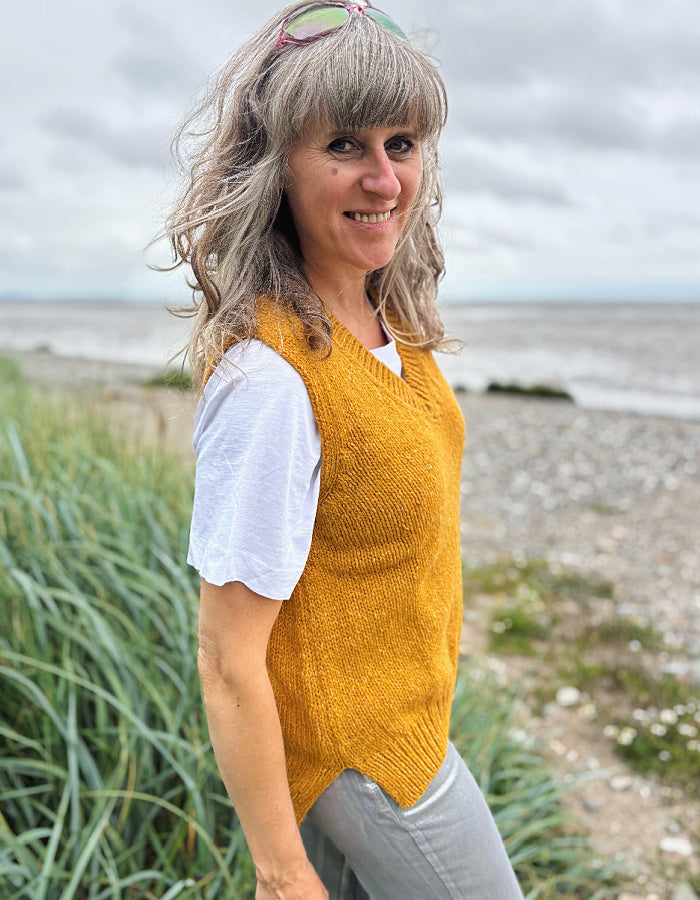 Woman wearing a yellow knitted vest on a beach