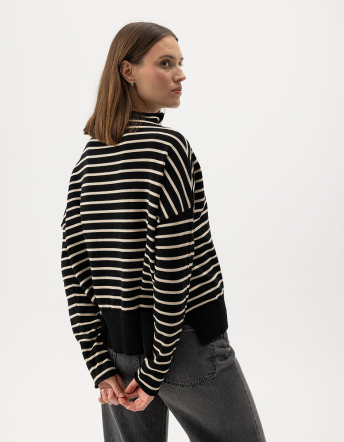Woman wearing a navy and cream striped cottonsweater on a white background