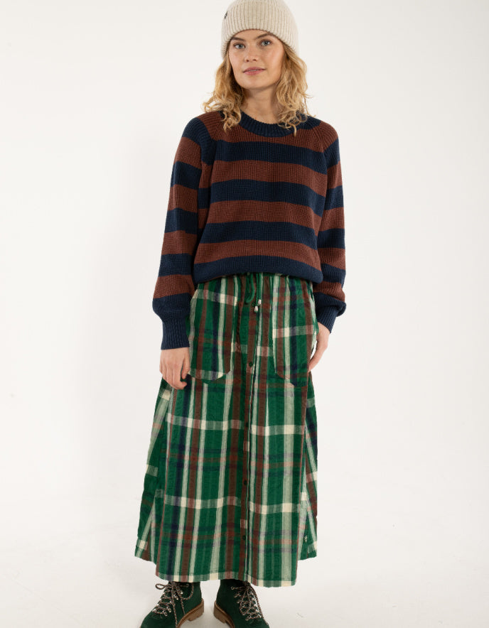 Woman wearing a striped sweater and plaid skirt on a white background