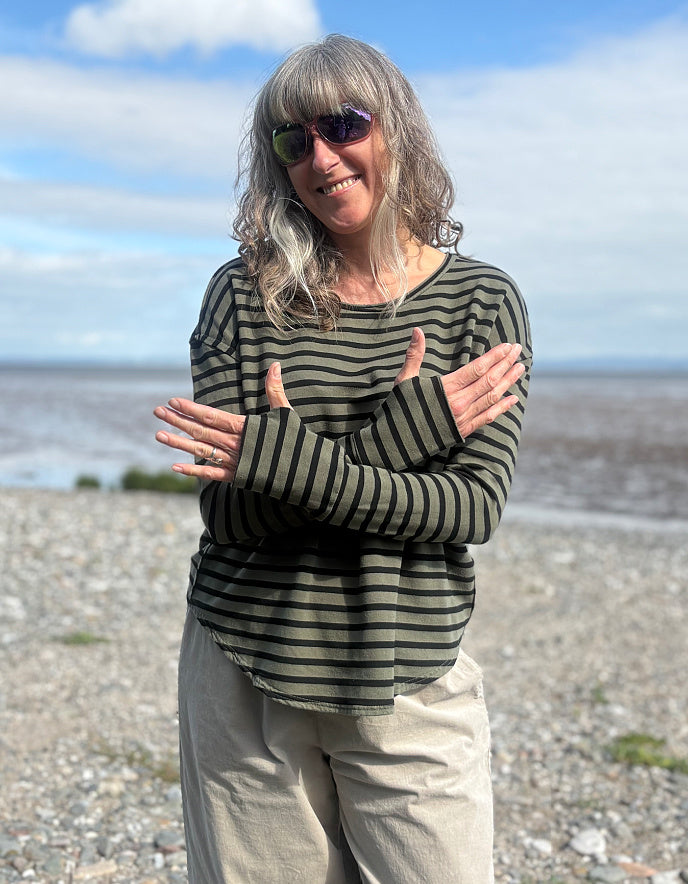 Woman wearing a striped shirt fleece t shirt with thumbholes and sunglasses on a beach