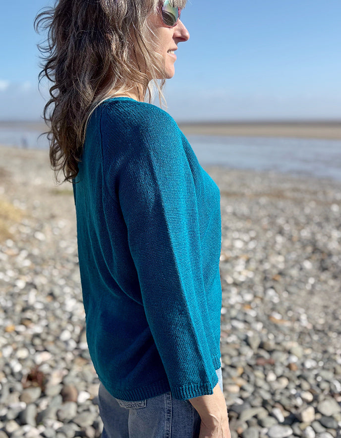 woman wearing turquoise linen knit sweater on the beach