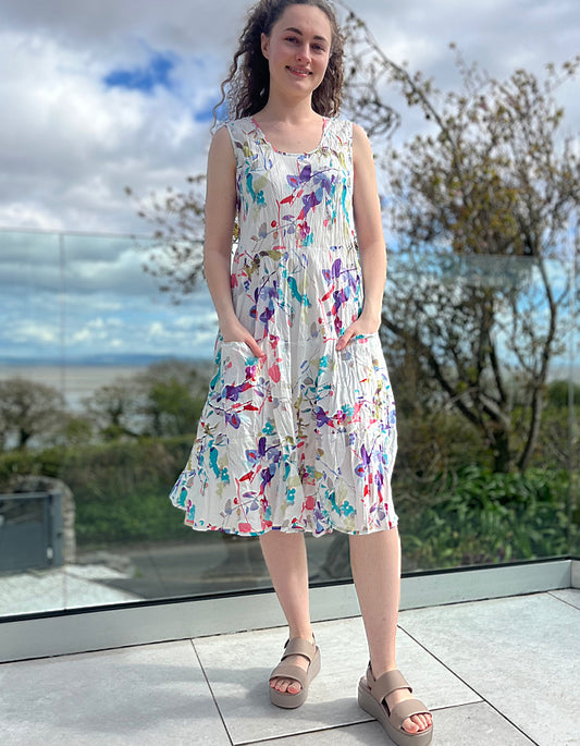 sleeveless cotton summer dress with tired flared shape and front patch pockets, pretty floral print in pinks and purples