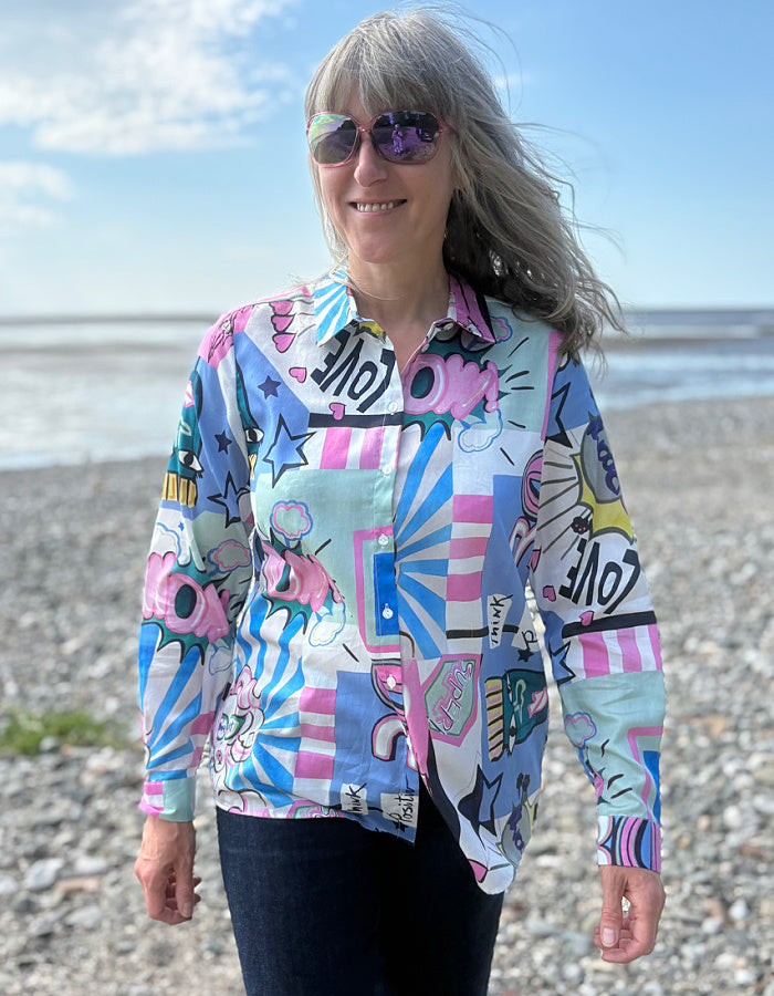 Person wearing a colorful patterned shirt on a beach