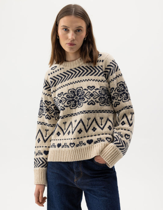 Woman wearing a cream Fairisle patterned scandi sweater on a white background
