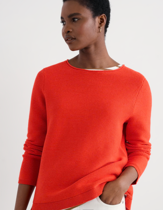 Woman wearing a bright orange sweater on a white background