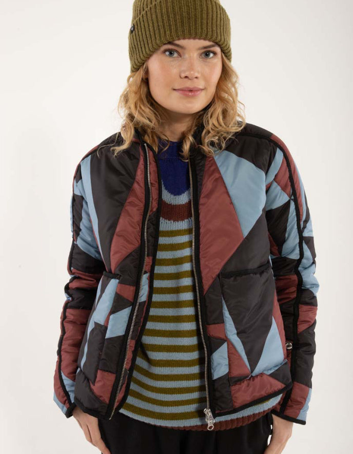 Person wearing a patterned jacket over a striped sweater on a white background