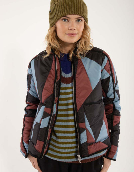 Person wearing a patterned jacket over a striped sweater on a white background