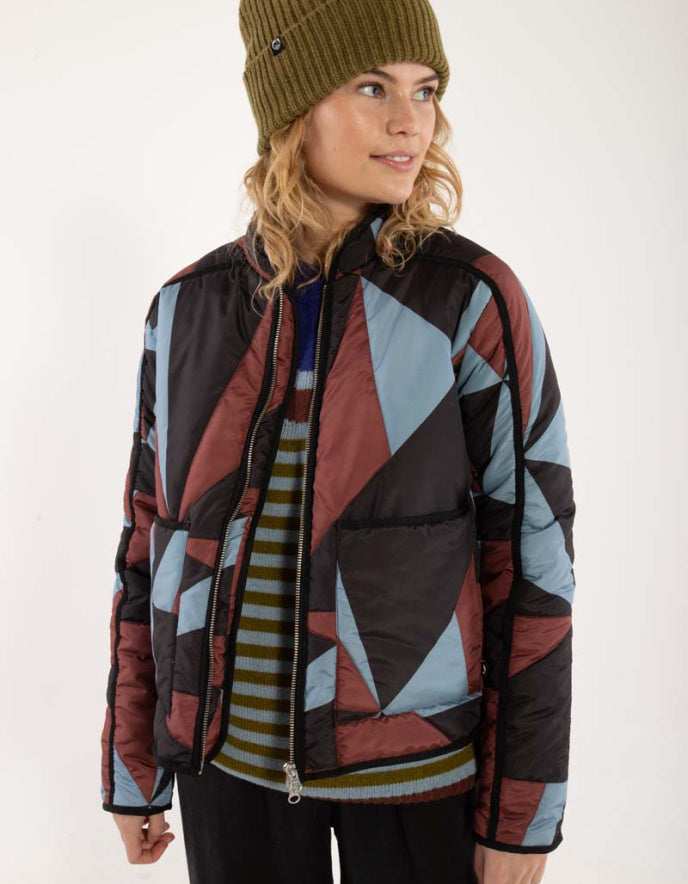 Person wearing a colourful geometric-patterned puffer jacket on a white background