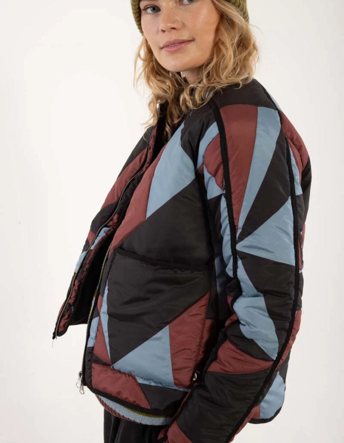 Person wearing a colourful geometric-patterned puffer jacket on a white background