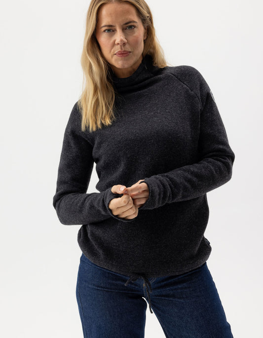 Woman wearing a dark gray turtleneck sweater and blue jeans on a white background