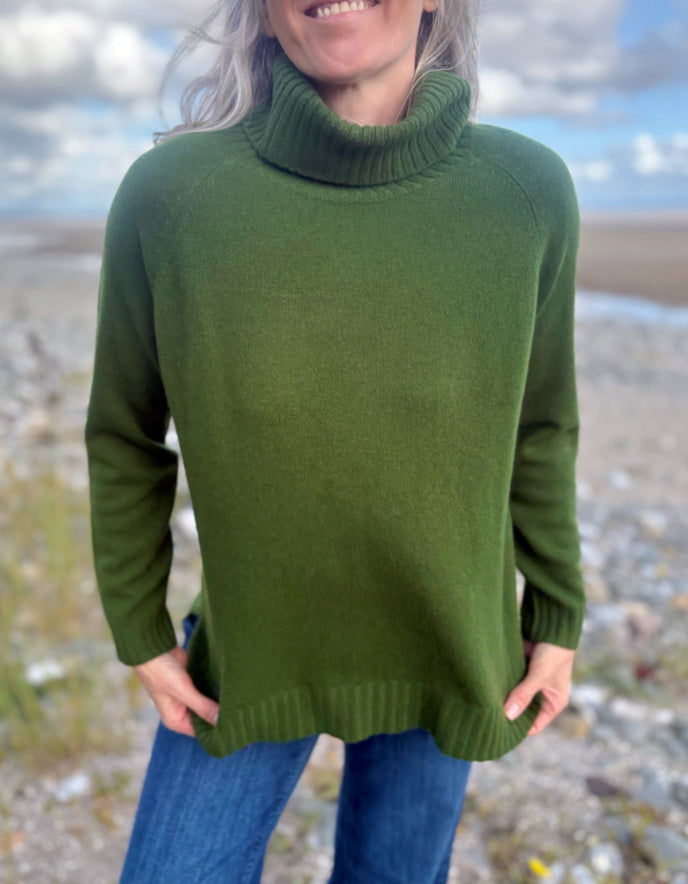 Person wearing a green sweater with a blurred natural background