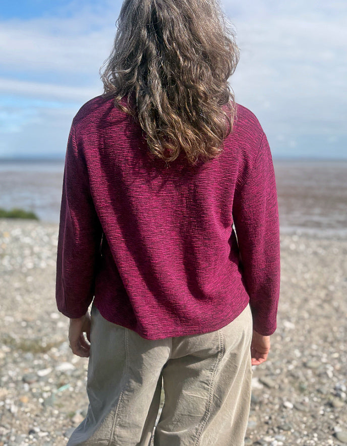Person wearing a maroon sweater on a beach