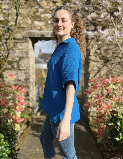 loose fit white over the head shirt with V neckline and collar, loose dropped shoulder with wide elbow length sleeve in gauzy cobalt blue cotton