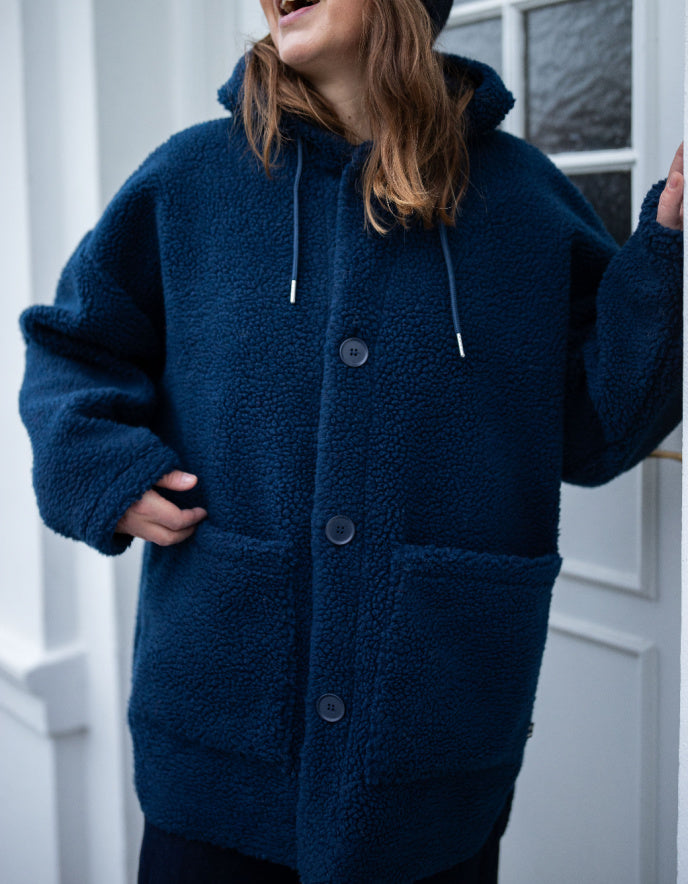 Person wearing a blue fleece jacket with a white door in the background