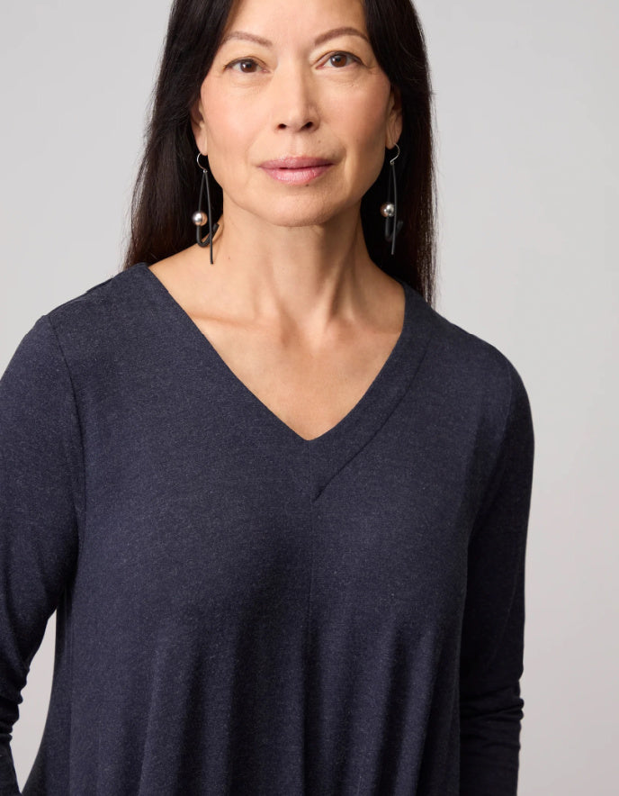 Woman wearing a dark blue long-sleeve dress against a plain background