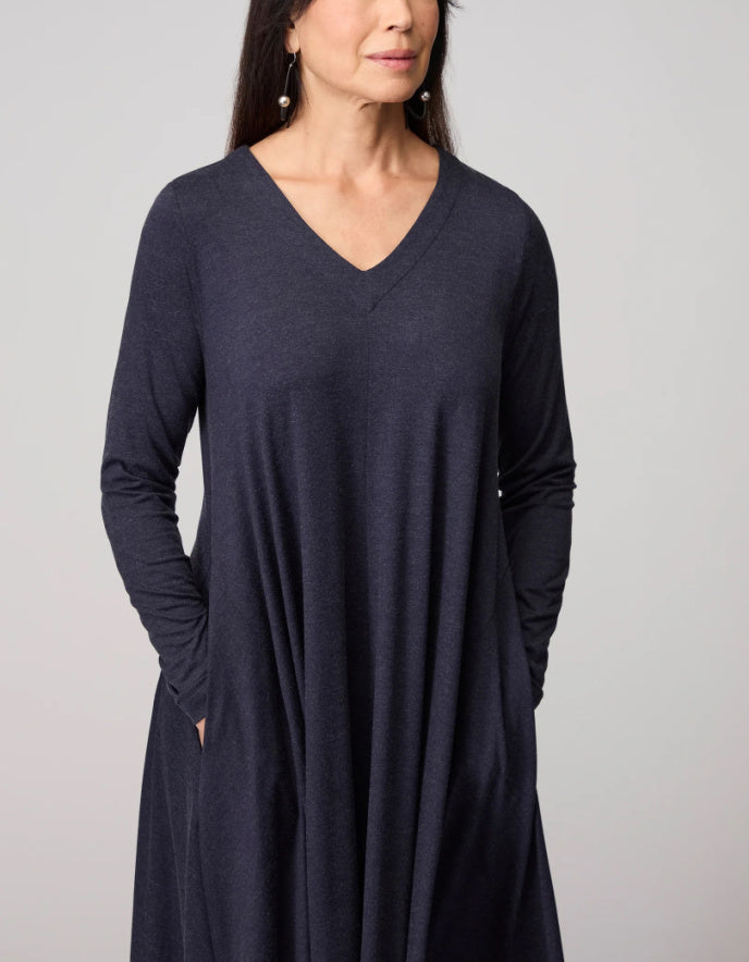 Woman wearing a long-sleeve navy dress against a plain background