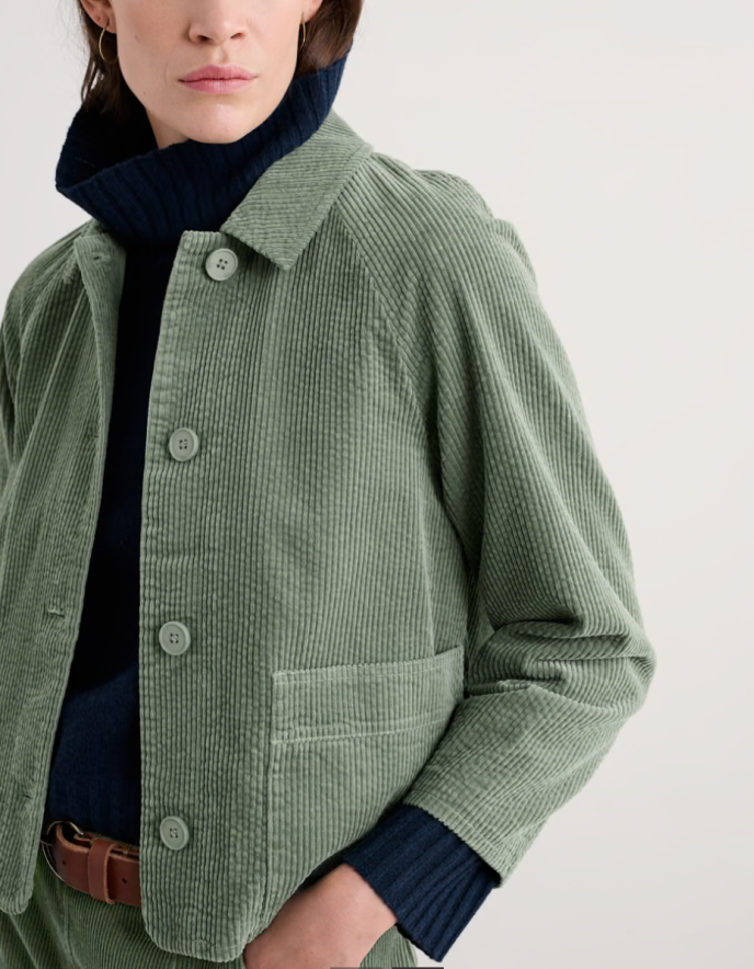 Person wearing sage green boxy fit cotton cord jacket with a white background