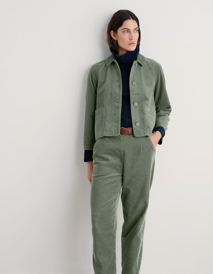Person wearing sage green boxy fit cotton cord jacket with a white background