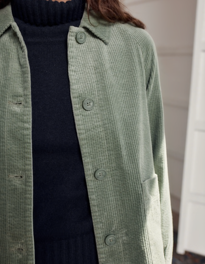 Person wearing sage green boxy fit cotton cord jacket with a white background