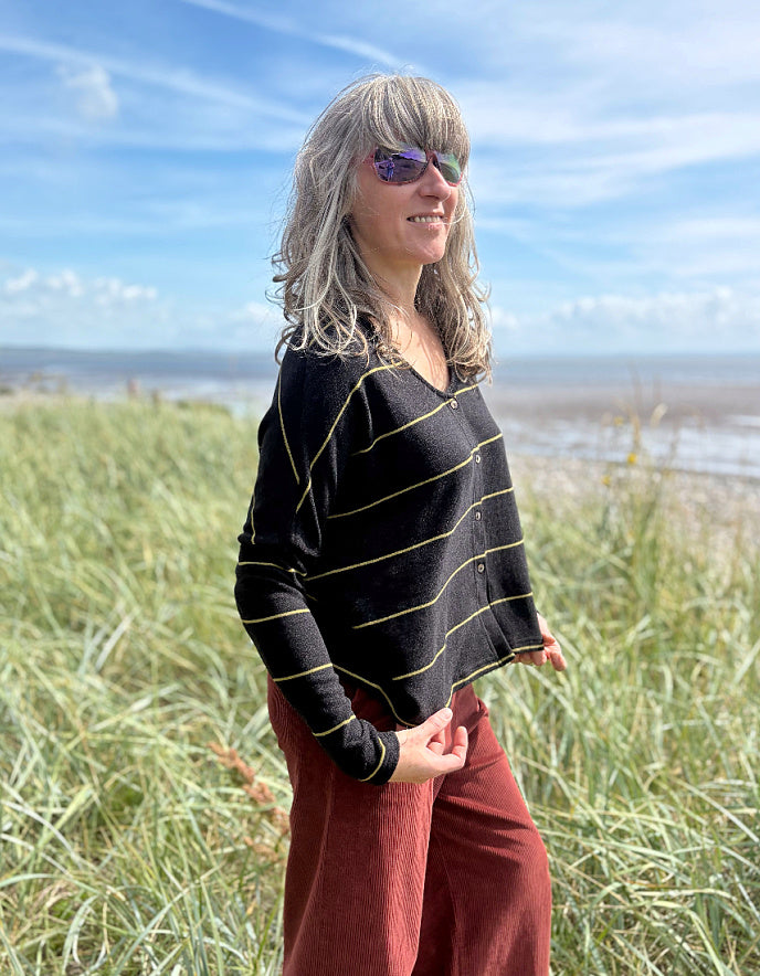 Woman standing in a grassy field with a blue sky and ocean in the background