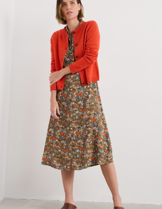 Woman wearing a red cardigan over a floral dress on a white background