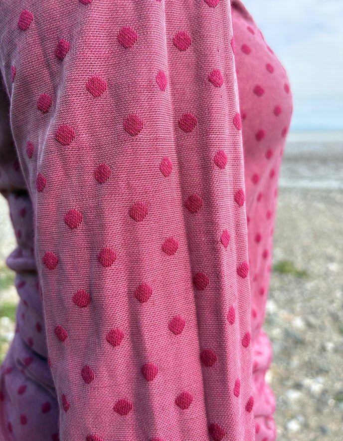 Close-up of a pink polka dot fabric with a blurred natural background