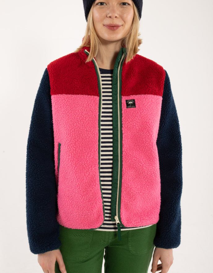 Person wearing a colorful fleece vest with red, pink, and navy sections on a white background