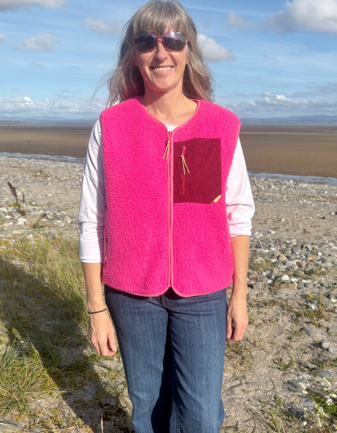 Person wearing a bright pink vest on a beach