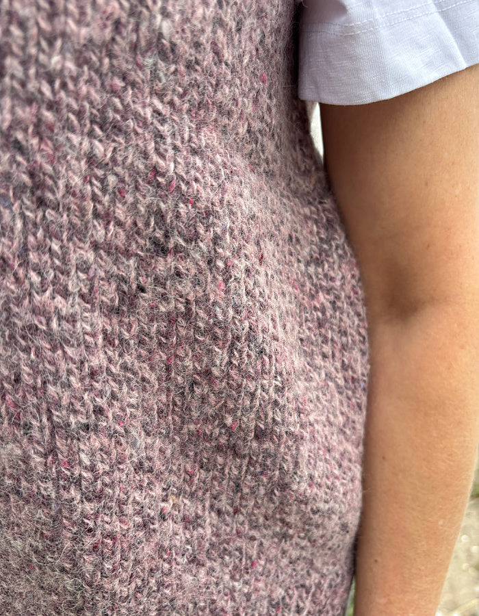 Close-up of a textured pink donegal tweed garment with a blurred background
