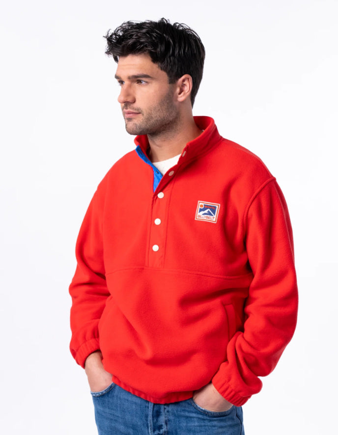 Man wearing a red pullover with a logo on a white background