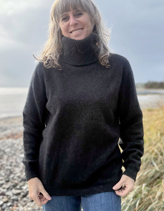 Person wearing a black sweater standing on a beach