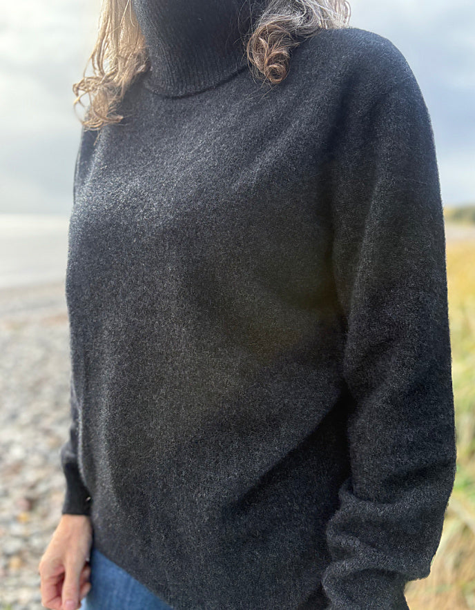 Person wearing a dark gray sweater in an outdoor setting