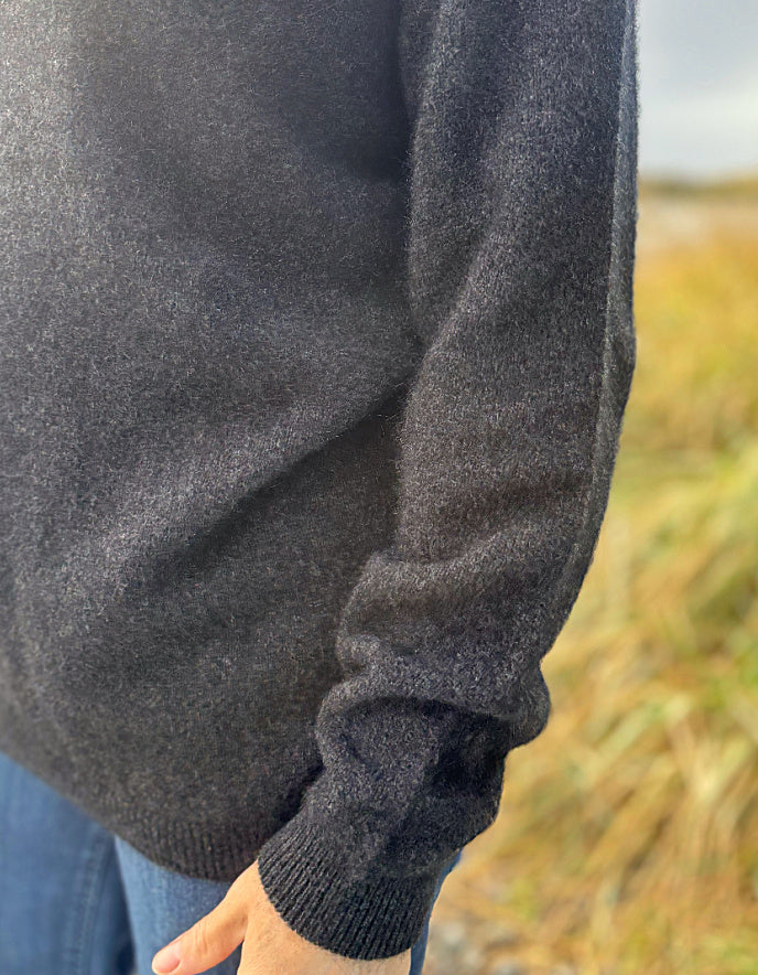 Dark gray sweater sleeve with a blurred natural background