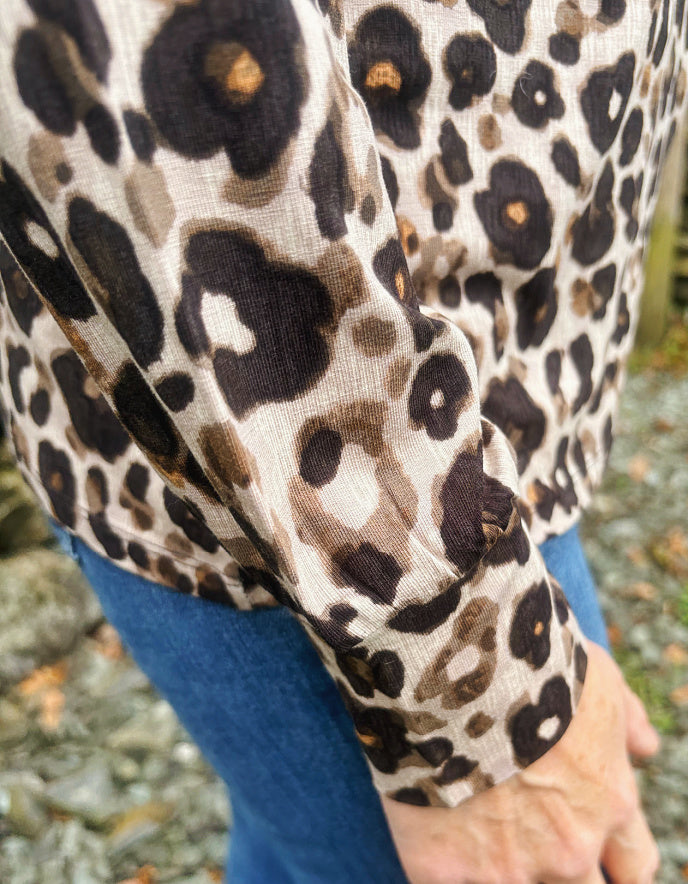 Person wearing a leopard print polo neck top with a blurred natural background