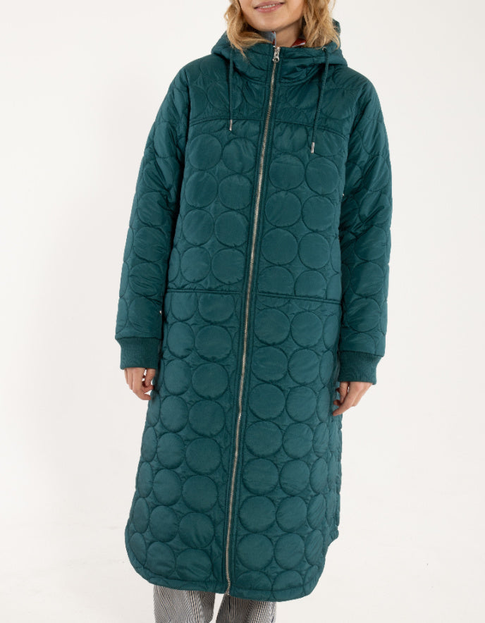 Person wearing a long teal quilted coat on a white background