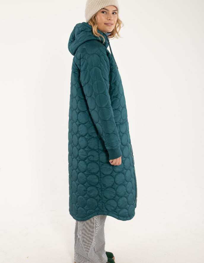 Person wearing a long teal quilted coat on a white background